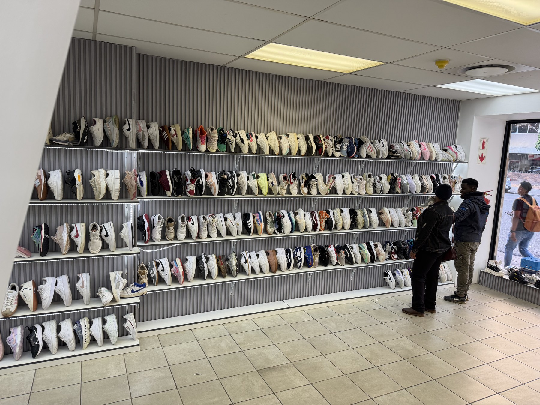 Customers browsing a full wall of pre-loved sneakers at Second Step Couture